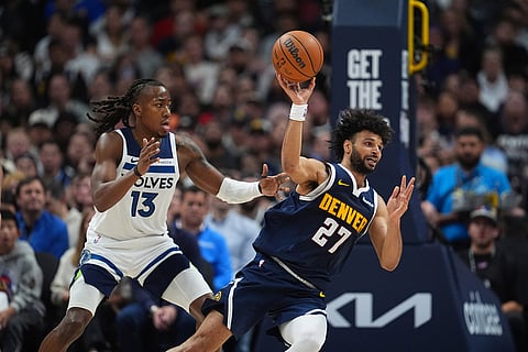 Denver Nuggets guard Jamal Murray, right, passes the ball as Minnesota Timberwolves guard Ayo Dosunmu defends in the second half in Game 5 of a first-round NBA playoffs basketball series in Denver.