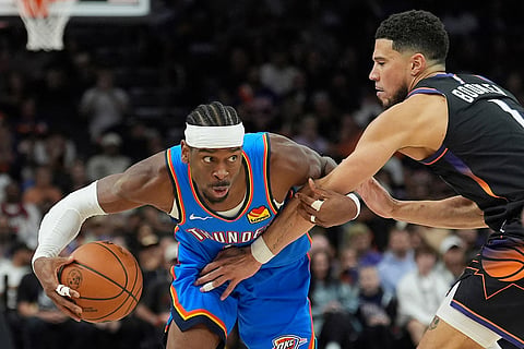 Oklahoma City Thunder guard Shai Gilgeous-Alexander, left, protects the ball from Phoenix Suns guard Devin Booker during the second half of Game 4 in a first-round NBA playoffs basketball series  in Phoenix.
