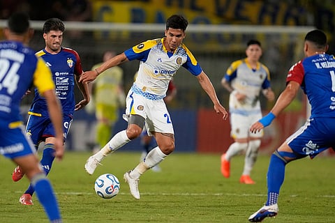 Guillermo Fernandez of Argentina's Rosario Central, center, goes for the ball during a Copa Libertadores Group H soccer match against Venezuela's Universidad Central in Caracas, Venezuela.