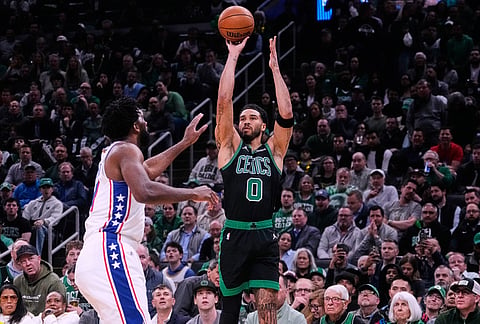 Boston Celtics forward Jayson Tatum (0) takes a 3-point shot over Philadelphia 76ers center Joel Embiid, left, during the first half of Game 5 of a first-round NBA playoffs basketball series, in Boston. 