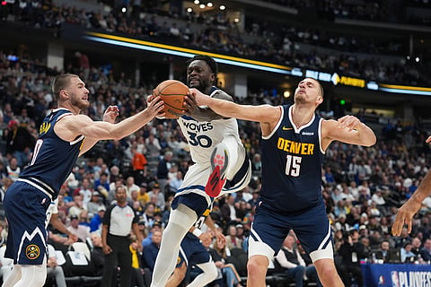Minnesota Timberwolves forward Julius Randle, center, fights for control of the ball while driving between Denver Nuggets guard Christian Braun, left, and center Nikola Jokic in the second half in Game 5 of a first-round NBA playoffs basketball series in Denver.