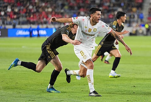 LAFC forward Jacob Shaffelburg (18) grabs Toluca midfielder Nicolas Castro (8) during the second half of the first leg of a CONCACAF Champions Cup semifinal soccer match in Los Angeles.
