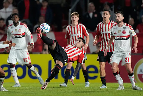 Facundo Farias of Argentina's Estudiantes de La Plata, center, kicks the ball during a Copa Libertadores Group A soccer match against Brazil's Flamengo in La Plata, Argentina.