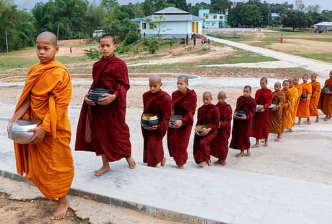 Buddhist (novice) monks walk in line after receiving food offerings on the eve of 'Buddha Purnima', also known as Vesak Day, on the outskirts of Agartala, Tripura.