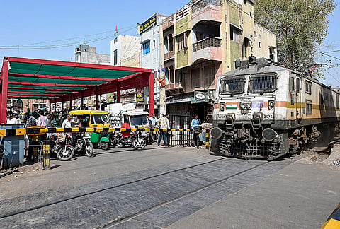 Commuters wait under a temporary shade arranged by local authorities to shield them from scorching heat near a railway crossing.