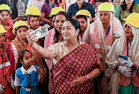 Delhi Chief Minister Rekha Gupta takes a selfie with workers during the International Labour Day event as she visits the Sant Nirankari Hospital construction site, at Dhirpur, in New Delhi.
