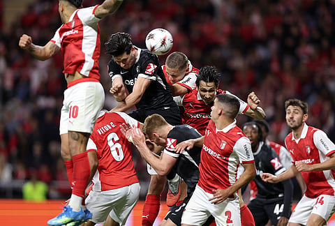 Braga, in red, and Freiburg players jump for the ball during the Europa League semifinal, first leg, soccer match between SC Braga and Freiburg in Braga, Portugal.