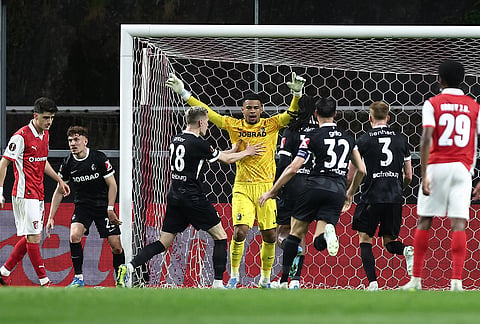 Freiburg players celebrate after Freiburg's goalkeeper Noah Atubolu, center, stopped a penalty shot during the Europa League semifinal, first leg, soccer match between SC Braga and Freiburg in Braga, Portugal.