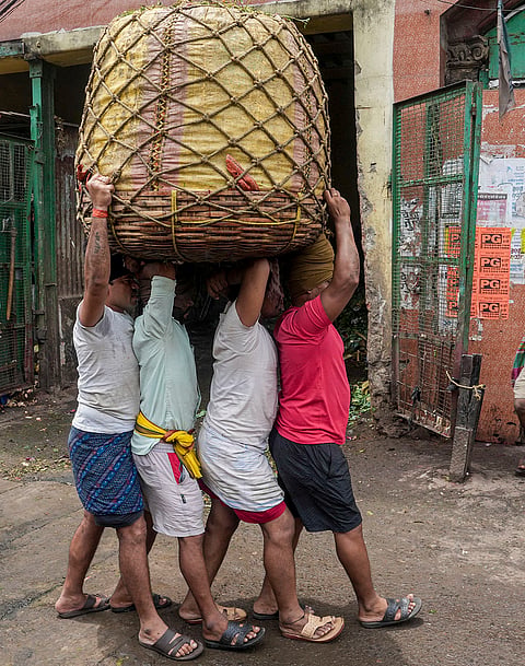 Workers carry a basket of vegetables at a wholesale vegetable market on International Labour Day, in Kolkata, West Bengal.
