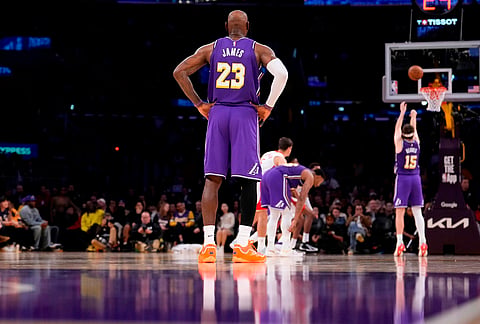 Los Angeles Lakers forward LeBron James, left, stands on the court as guard Austin Reaves, right, shoots a free throw during the second half in Game 5 of a first-round NBA playoffs basketball series against the Houston Rockets, in Los Angeles.
