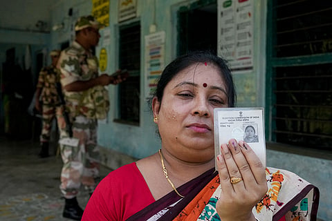 A voter shows her ink-marked fingers and her identity card after casting her vote during a repoll for the West Bengal Assembly elections, ordered by the Election Commission following reports of electoral malpractices, at Magrahat Paschim constituency, in South 24 Parganas district.