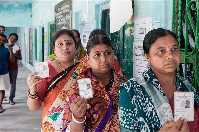 Voters shows their identity cards as they wait in a queue to cast their votes at a polling station during a repoll ordered by the Election Commission following reports of electoral malpractices, at Magrahat Paschim constituency, in South 24 Parganas district, West Bengal. - | Photo: PTI/Swapan Mahapatra