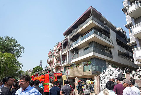 People gather outside a four-storey residential building where a fire killed at least nine people, at Vivek Vihar area, in New Delhi.