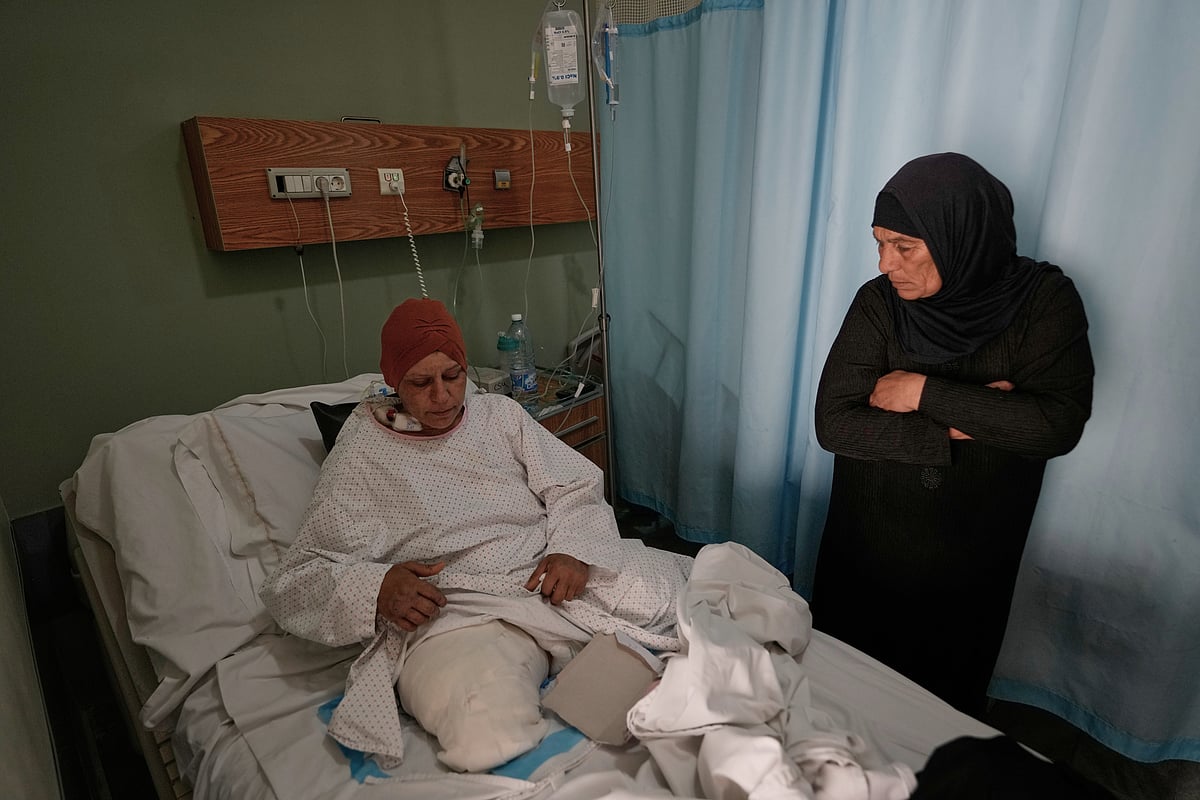Sanaa Khalil, 35, a Syrian farmer who lost her two legs in the past days by an Israeli airstrike while she was working at a banana plantation, lies on a bed as she is assisted by a relative at a hospital in the southern port city of Tyre, Lebanon, Friday, May 1, 2026. - Hussein Malla; AP