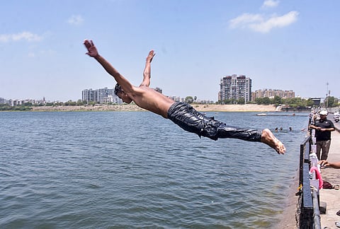 A man dives into a river to beat the heat on a hot summer day, in Surat, Gujarat.