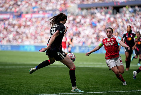 Lyonnes' Jule Brand, left, scores her side's third goal during the Women's Champions League semifinal, second leg, soccer match between OL Lyonnes and Arsenal, in Decines, outside Lyon, France.