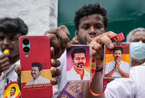 Supporters hold portraits of Tamilaga Vettri Kazhagam (TVK) chief Vijay during vote tabulation on the day of Assembly election results, in Chennai.