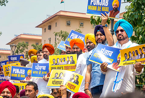 AAP MLA from Punjab Labh Singh Ugoke, third right, and others hold placards during a protest, in New Delhi.