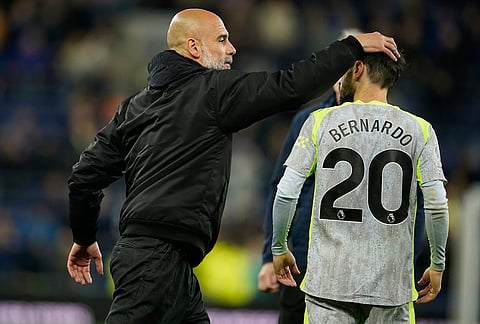 Manchester City's head coach Pep Guardiola hugs Bernardo Silva after the Premier League soccer match between Manchester City and Everton in Liverpool, England.