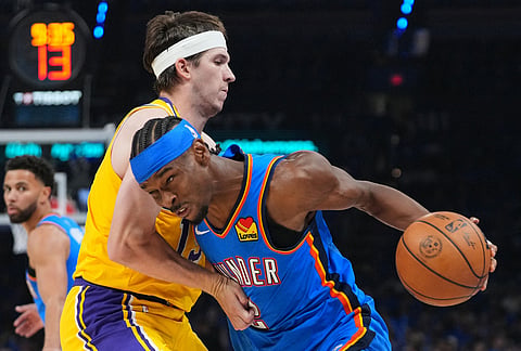 Oklahoma City Thunder guard Shai Gilgeous-Alexander, right, drives to the basket as Los Angeles Lakers guard Austin Reaves, left, defends second half of Game 1 in a second-round NBA basketball playoffs series in Oklahoma City. 