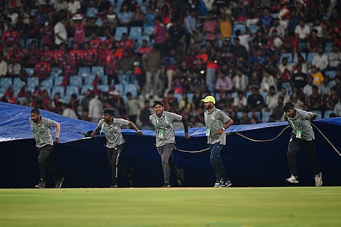 Ground staff pull rain covers to the field as it drizzles during the Indian Premier League cricket match between Royal Challengers Bengaluru and Lucknow Super Giants in Lucknow, India.
