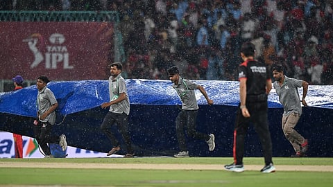 Ground staff pull rain covers to the field as it drizzles during the Indian Premier League cricket match between Royal Challengers Bengaluru and Lucknow Super Giants in Lucknow, India, Thursday, May 7, 2026