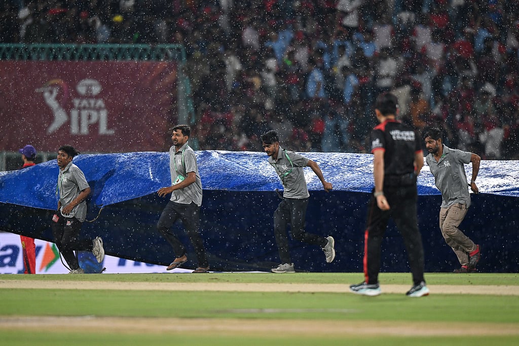 Ground staff pull rain covers to the field as it drizzles during the Indian Premier League cricket match between Royal Challengers Bengaluru and Lucknow Super Giants in Lucknow, India, Thursday, May 7, 2026.