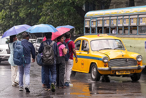 People walk with umbrellas during rainfall, in Kolkata.