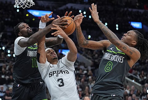 San Antonio Spurs forward Keldon Johnson (3) battles Minnesota Timberwolves center Naz Reid (11) and guard Bones Hyland (8) for a rebound during the second half in Game 2 of a second-round NBA playoffs basketball series in San Antonio.