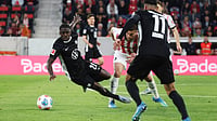 Bundesliga Matchday 33 Preview: Key Matchups, Players To Watch, Injury List – All You Need To Know | Photo: dpa/Philipp von Ditfurth via AP : Wolfsburg Saël Kumbedi, left, and Freiburg's Lucas Höler, centre, challenge for the ball during the German Bundesliga soccer match between SC Freiburg and VfL Wolfsburg in Freiburg im Breisgau, Germany, Sunday, May 3, 2026.