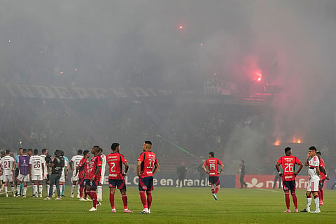 Players of Colombia's Independiente Medellin and Brazil's Flamengo stand on the field after the match was temporarily suspended because of crowd trouble during a Copa Libertadores Group A soccer match in Medellin, Colombia.