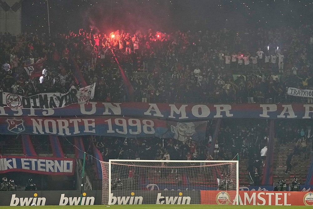 Fans of Colombia's Independiente Medellin light flares as the match against Brazil's Flamengo was temporarily suspended because of crowd trouble during a Copa Libertadores Group A soccer match in Medellin, Colombia. - | Photo: AP/Fernando Vergara