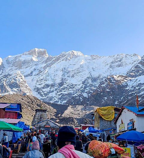 People throng at the premises of Kedarnath Dham as fresh snowfall blankets the surrounding mountains, in Rudraprayag district, Uttarakhand.