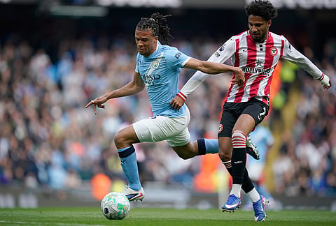 Manchester City's Nathan Ake, left, and Brentford's Kevin Schade challenge for the ball during the English Premier League soccer match between Manchester City and Brentford in Manchester.