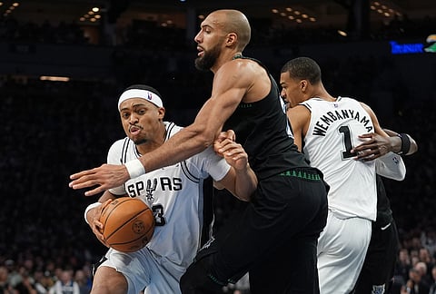San Antonio Spurs forward Keldon Johnson (3) drives against Minnesota Timberwolves center Rudy Gobert, center, during the second half of Game 3 of a NBA basketball second-round playoff series in Minneapolis.