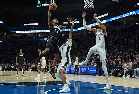 Minnesota Timberwolves guard Ayo Dosunmu (13) drives to the basket against San Antonio Spurs guard Stephon Castle (5) and forward Victor Wembanyama (1) during the first half of Game 3 of a NBA basketball second-round playoff series in Minneapolis.