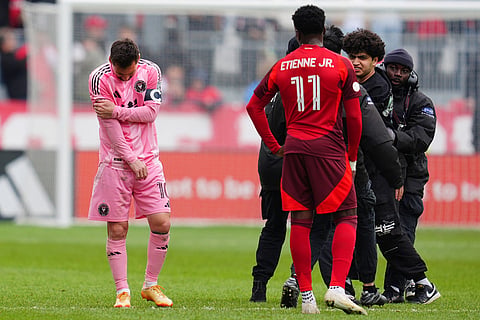 Inter Miami CF midfielder Lionel Messi (10) grabs his arm as security escorts a fan off the field who grabbed him during second half MLS soccer against Toronto FC, in Toronto.