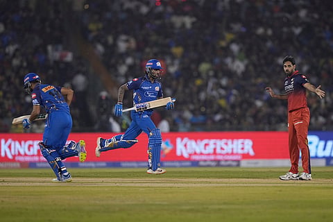 Mumbai Indians' Naman Dhir, left, and Tilak Varma run between the wickets as Royal Challengers Bengaluru's Bhuvneshwar Kumar reacts during the Indian Premier League cricket match between Royal Challengers Bengaluru and Mumbai Indians in Raipur, India.