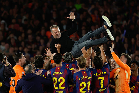 Barcelona head coach Hansi Flick is lifted up by his players after winning the Spanish La Liga soccer match between FC Barcelona and Real Madrid that makes them Spanish league champions in Barcelona, Spain.