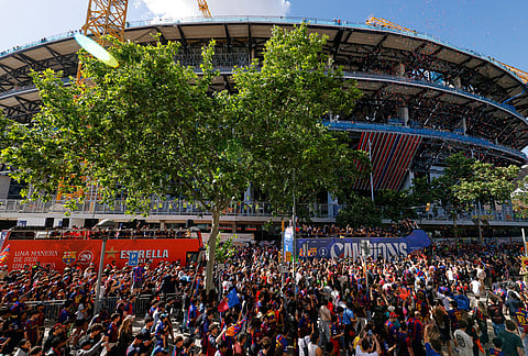 Surrounded by supporters, FC Barcelona players celebrate atop a bus after winning the Spanish La Liga title in Barcelona, Spain.