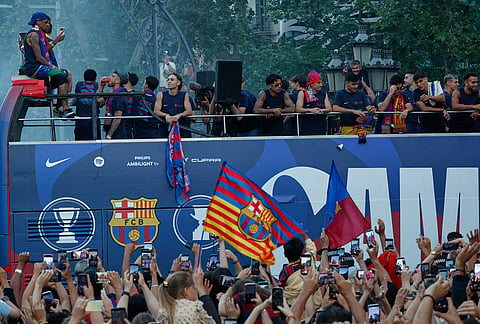 Surrounded by supporters, FC Barcelona players celebrate atop a bus after winning the Spanish La Liga title in Barcelona, Spain.