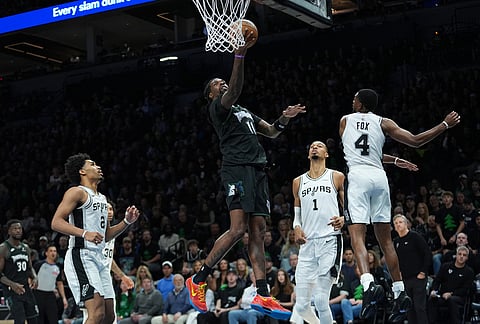 Minnesota Timberwolves center Naz Reid (11) drives to the basket against San Antonio Spurs forward Victor Wembanyama (1) and guard De'aaron Fox (4) during the first half of Game 4 of an NBA basketball second-round playoffs series in Minneapolis.