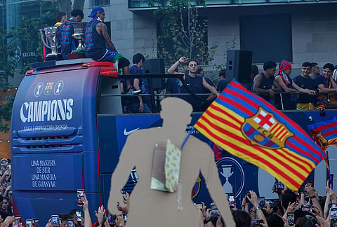 Surrounded by supporters, FC Barcelona players celebrate atop a bus after winning the Spanish La Liga title in Barcelona, Spain.