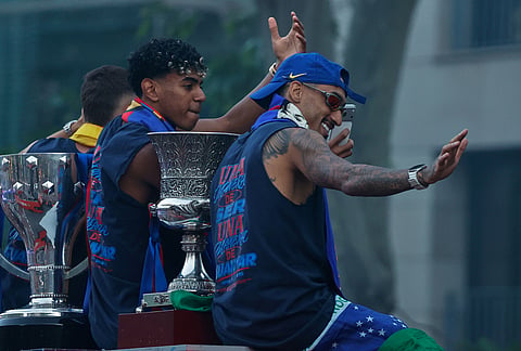 FC Barcelona players Lamine Yamal, left, and Raphinha celebrate atop a bus after winning the Spanish La Liga title in Barcelona, Spain.