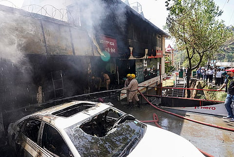 Firefighters at the site after a fire broke out at a showroom, in the Kacchighati area of Shimla.