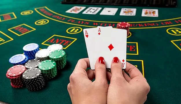 Hands holding two aces over a casino poker table