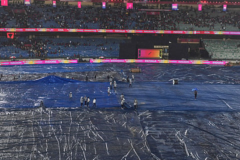 Groundsmen cover the ground before the start of the Indian Premier League cricket match between Royal Challengers Bengaluru and Kolkata Knight Riders in Raipur, India.