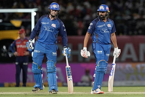 Mumbai Indians' Rohit Sharma, right, and batting partner Ryan Rickelton stand between the wickets during the Indian Premier League cricket match between Punjab Kings and Mumbai Indians in Dharamshala, India.
