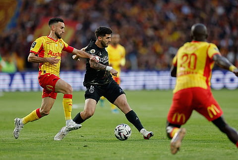 PSG's Lucas Beraldo, center, challenges for the ball with Lens' Adrien Thomasson, left, during the French League One soccer match between Lens and Paris Saint Germain, in Lens, northern France.