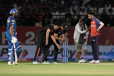 Punjab Kings' Yuzvendra Chahal, right, and Mumbai Indians' Rohit Sharma, left, watch as umpires fix the stumps after an unsuccessful run-out during the Indian Premier League cricket match between Punjab Kings and Mumbai Indians in Dharamshala, India.